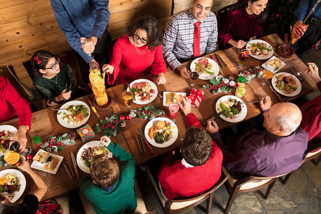 Celebrate the holdidays at Rodizio a group of people sitting at a table with drinks